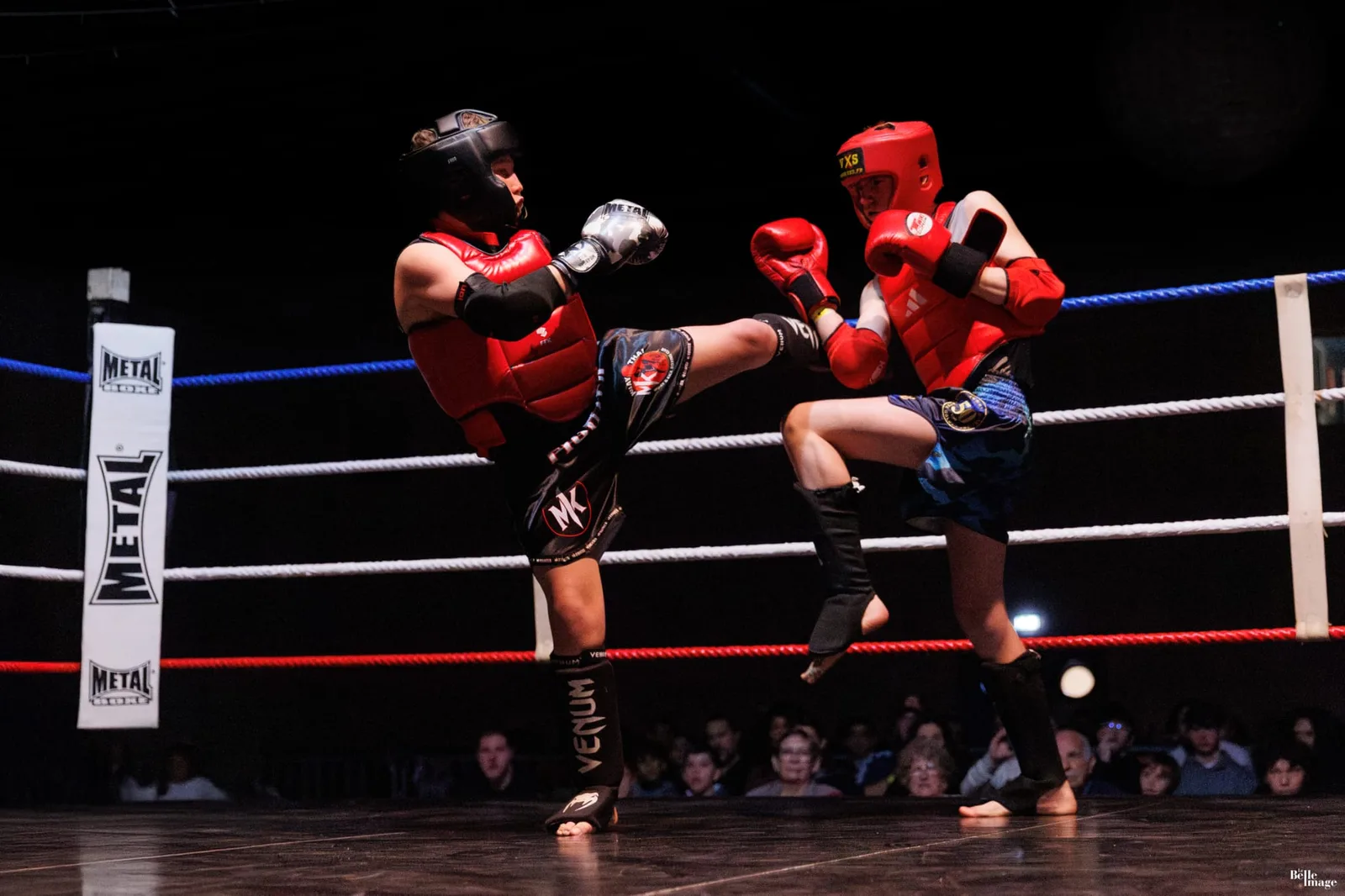 Deux jeunes combattants du club échangent des coups de pied sur le ring lors d’un gala de muay thaï